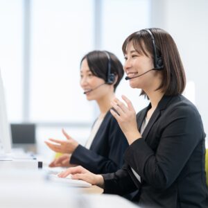 ヘッドセットを着けてパソコンに向かい通話するコールセンターの担当者2名